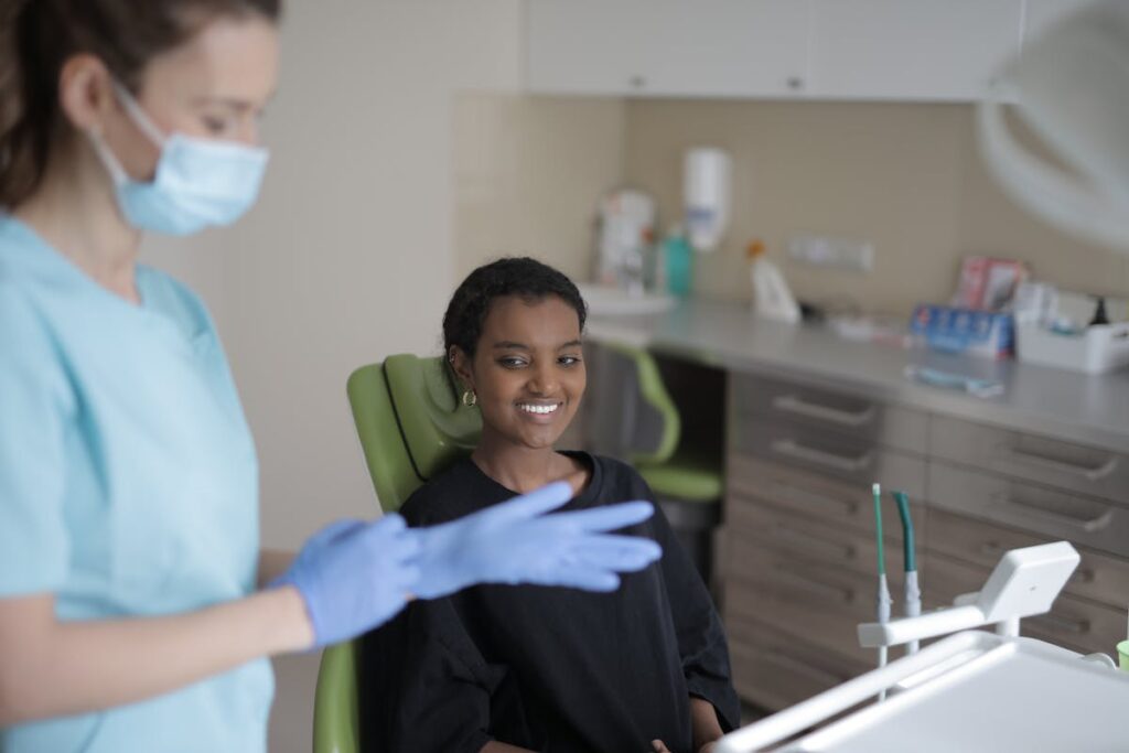 Cheerful young ethnic female patient waiting for teeth treating in dentist room