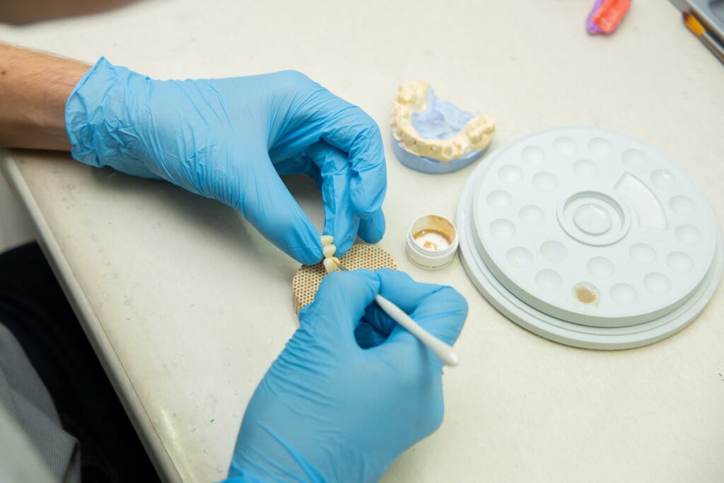 Hands of crop specialist making dental implants