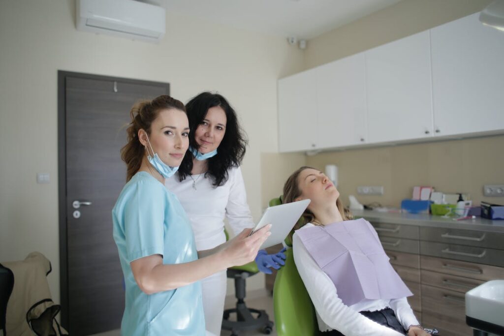 Medical staff with tablet and lying patient in dental clinic