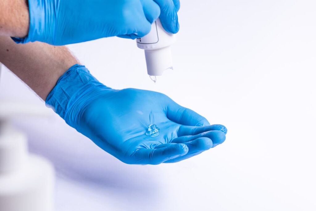 Unrecognizable doctor applying antiseptic on gloves